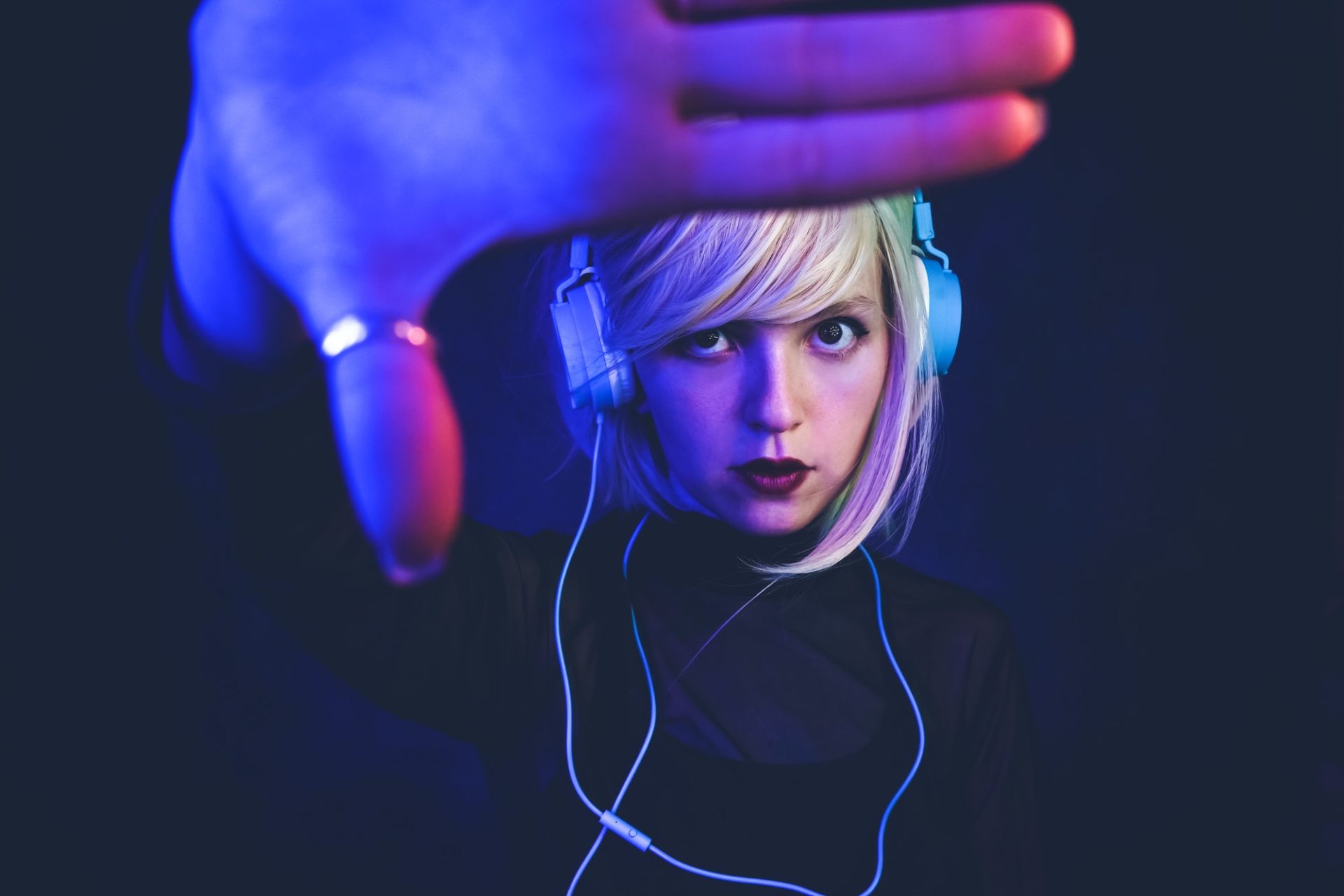 Young woman listening to music and illuminated by neon lights