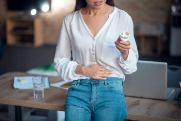 Pleasant young woman putting hand on her stomach