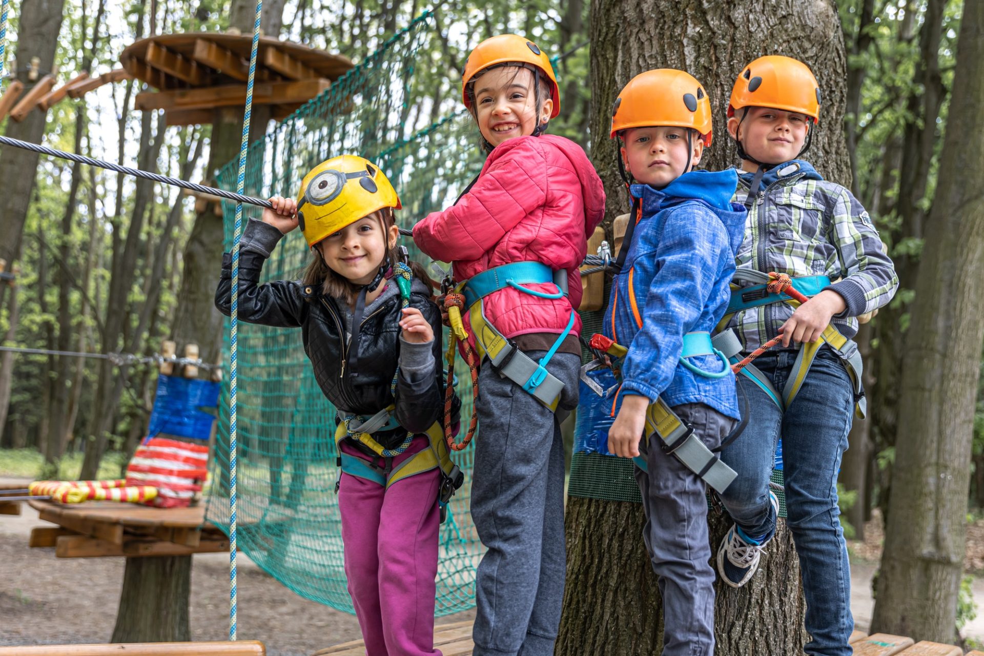Children in a climbing park in protective helmets climb the ropes.