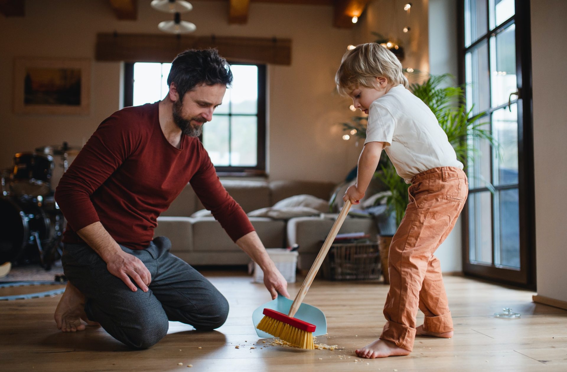 Father with small son sweeping at home, daily chores concept