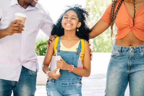 Little girl going to the school with her parents.