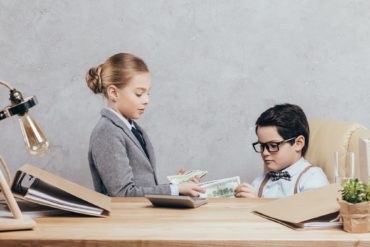 side view of little boy and girl counting money at workplace