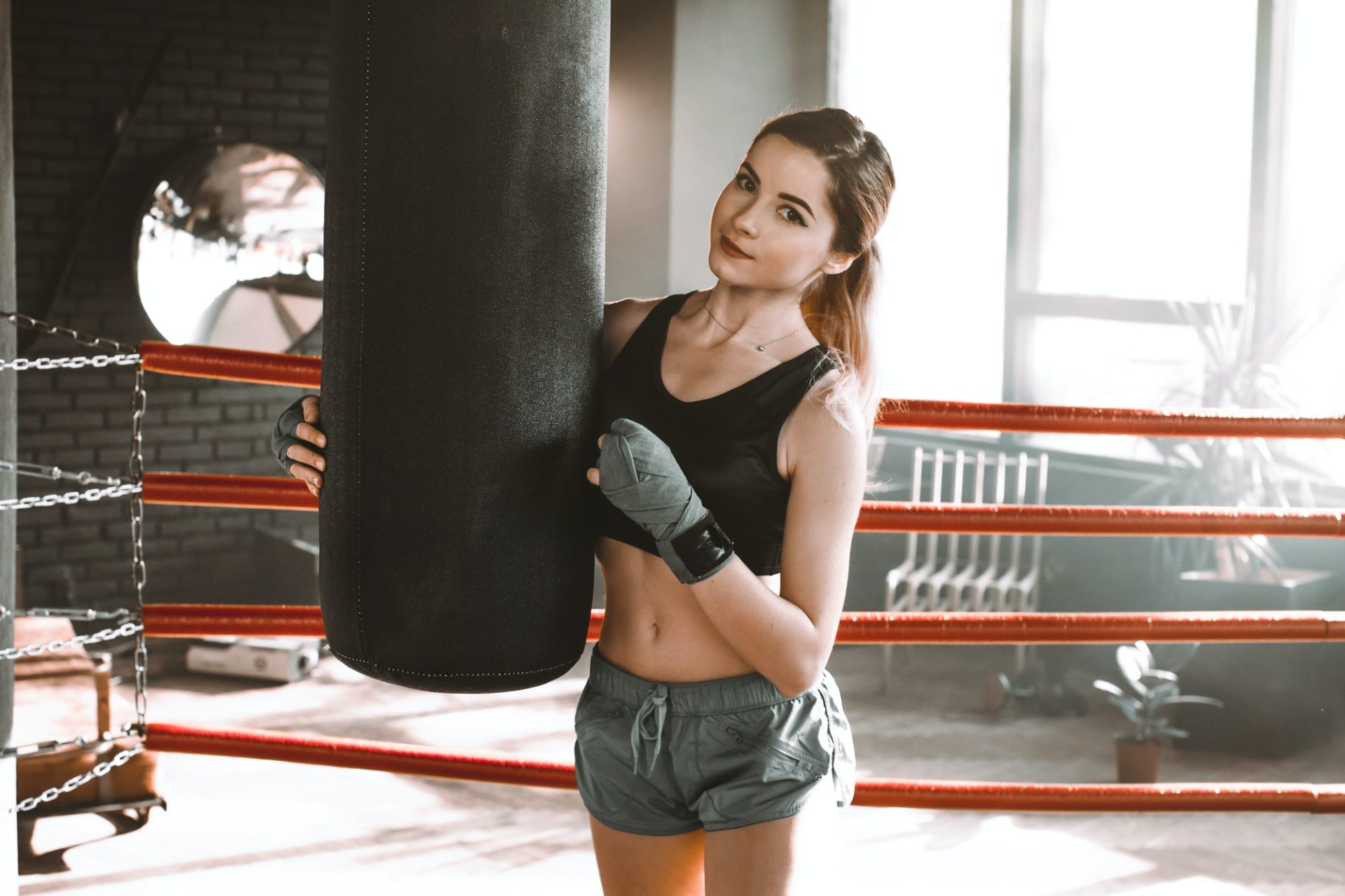 Young woman doing boxing training at the gym, she is wearing boxing gloves and hitting the punching